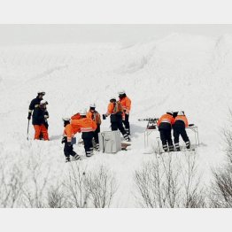 誰のせいか？（雪崩事故の現場周辺を調べる消防隊員ら）／（Ｃ）共同通信社