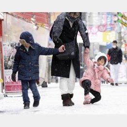 転びそうになりながら歩く親子連れ（２０１６年西日本大雪・福岡市）（Ｃ）共同通信社