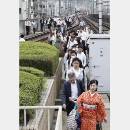 停止した電車から降りて線路を歩く人々（Ｃ）共同通信社