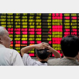 株価ボードを不安げに眺める投資家（Ｃ）ロイター