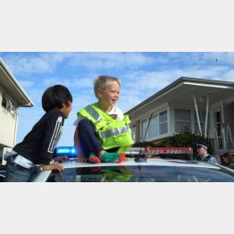 パトカーの上で笑顔のザッカリー君（オークランド市警のフェイスブックに投稿された動画より）