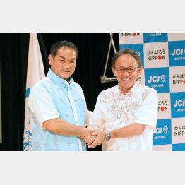 握手する玉城デニー氏（左）と佐喜真淳氏（Ｃ）日刊ゲンダイ