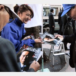 街頭演説会場で配られるマニフェストの冊子を手にする有権者たち（Ｃ）共同通信社