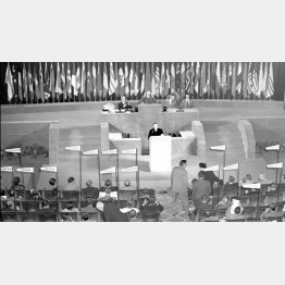 1951（昭和26）年9月7日夜、各国演説の最後の49番目に登壇し、対日講和条約の受諾演説をする吉田茂首席全権（中央）。議長はアチソン米国務長官。背景の参加国の旗はこの時点で51本で、日章旗は翌８日午前の講和条約調印式で初めて右端に掲揚された（Ｃ）共同通信社