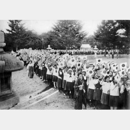 満州国を国家として認める「日満議定書」調印祝賀に駆り出され靖国神社で日の丸を振る女学生。国際世論は国際連盟からリットン調査団を派遣するなど「満州国は傀儡国家」との見方が多く、機先を制して既成事実化する狙いがあった（1932年9月15日）／（日本電報通信社撮影）