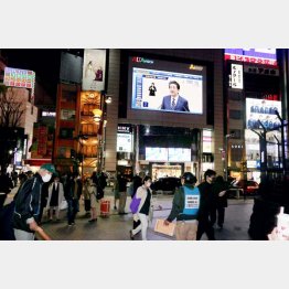 「緊急事態宣言」後の安倍首相の会見がヴィジョンで映し出されるなか、足早に過ぎる人々（新宿アルタ前＝7日夜）／（Ｃ）日刊ゲンダイ