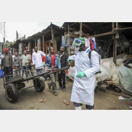 ケニアの首都ナイロビの屋外市場で、手押し車に消毒剤をかける保健省当局者（Ｃ）AP＝共同