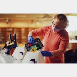 本を専用ボックスに入れるケリーさん（「ウイング」のツイッターから）