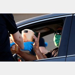 カリフォルニア・インダストリーのドライブイン・シアターで飲み物とポップコーンを受け取る観客（Ｃ）ロイター