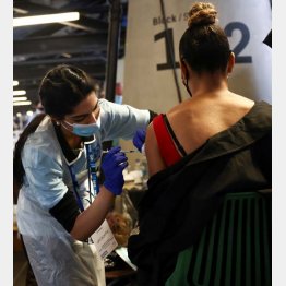 ファイザー製のワクチン接種を受ける女性（英、ロンドン）／（Ｃ）ロイター