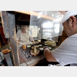 店主の塩見達二郎さんがコテと箸で形を整えた生地に夫人の充代さんが焼き色をつけていく（Ｃ）日刊ゲンダイ