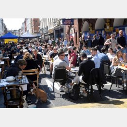 外の席で食事を楽しむ人びと（ロンドン）／（Ｃ）ロイター