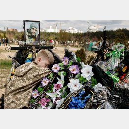 イースターから7日後の「死者記念ミサ」で父親の墓にすがりつく10歳の少年（首都キーウ近郊イルピンの墓地）／（Ｃ）ロイター