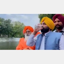 すくった水を飲む干すマン州首相（アーム・アードミ党のツイッターから）