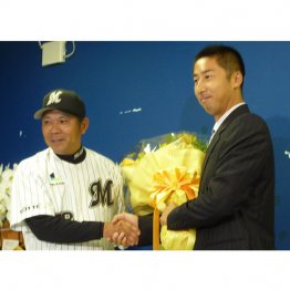 2012年に現役引退を表明し、ロッテの西村得文監督（左）と握手を交わす打撃守備コーチ兼内野手だった筆者（Ｃ）共同通信社