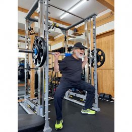 バーベルを担いでワイドスクワットをする筆者（本人提供）