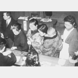 衆院選の投票所で投票用紙を受け取る女性たち。日本で女性が初めて投票した（1946＝１昭和21＝年4月10日、東京都葛飾区）／（Ｃ）共同通信社