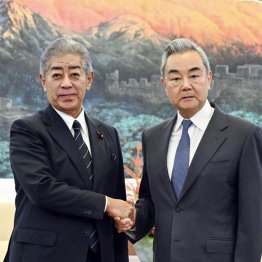 異例の厚遇（中国の王毅外相＝右、と握手する岩屋毅前外相）／（新華社＝共同）